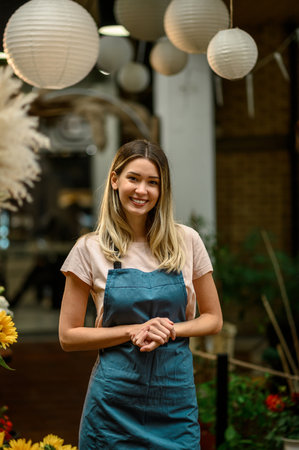 Portrait of beautiful florist working in flower shop while smiling and looking at a cameraの写真素材