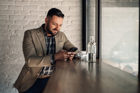 Handsome businessman using a smartphone while drinking coffee in a cafeの写真素材
