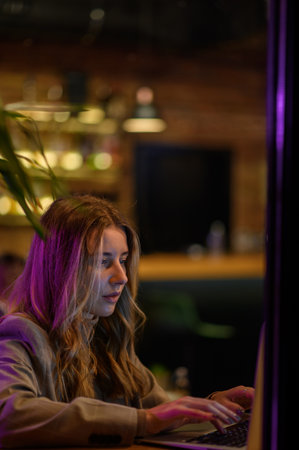 Young beautiful woman working on her laptop while sitting in a cafeの写真素材