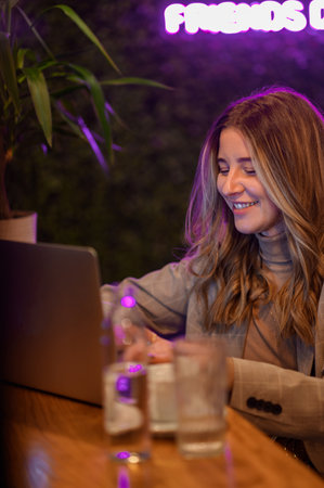 Young beautiful woman working on her laptop while drinking coffee in a cafeの写真素材