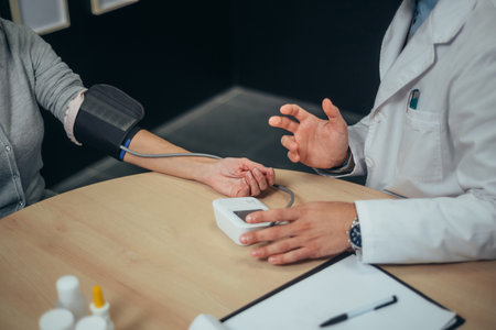 Male doctor measuring blood pressure of a senior woman patient in a modern office