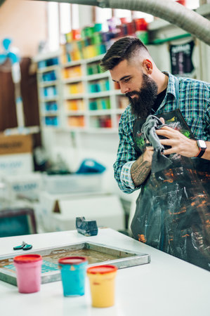 Male worker mixing colors for screen printing in a workshopの写真素材