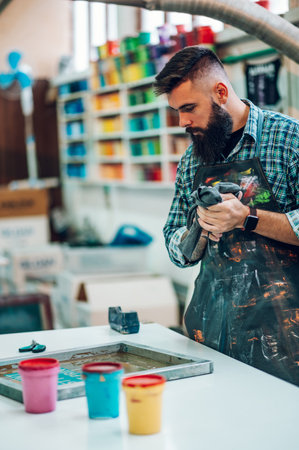 Male worker mixing colors for screen printing in a workshopの写真素材