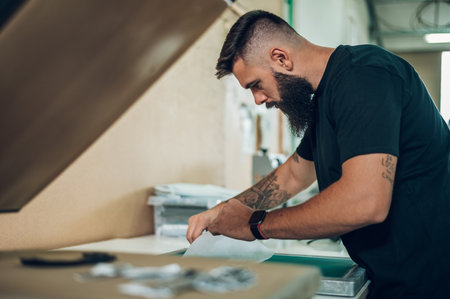 Male worker preparing screen printing film in workshopの写真素材