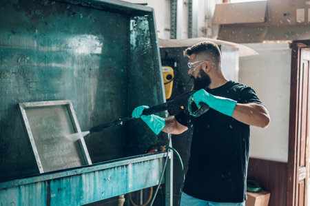 Male worker cleaning screen frame with water in a printing workshopの写真素材