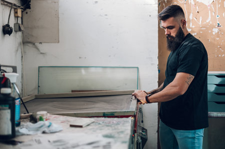 Male worker using a screen exposure unit while working in a printing workshopの写真素材