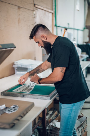 Male worker preparing screen printing film in workshopの写真素材