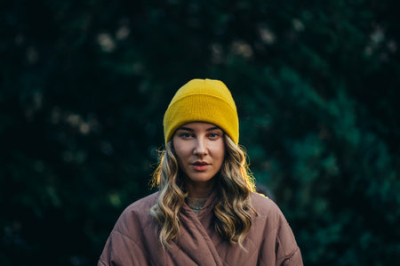 Beautiful young stylish woman wearing coat and a cap in the parkの写真素材