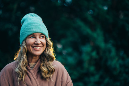 Beautiful young stylish woman wearing coat and a cap in the parkの写真素材