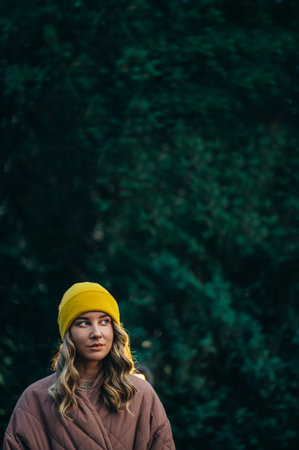 Beautiful young stylish woman wearing coat and a cap in the park