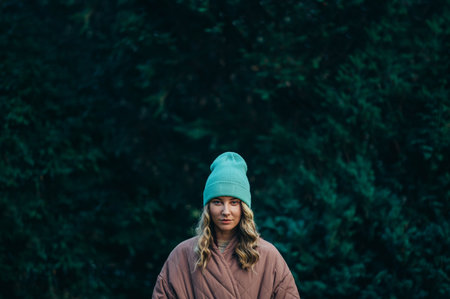Beautiful young stylish woman wearing coat and a cap in the parkの写真素材