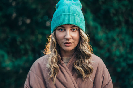 Beautiful young stylish woman wearing coat and a cap in the parkの写真素材