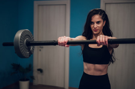 Attractive young woman training in the gym and using barbellの写真素材