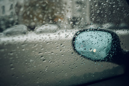 Drivers point of view while driving in the city during a bad weather. Snow in the city streets. Focus on drops on the windowの写真素材