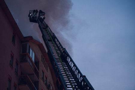 Firefighters put out a fire in a burning building while in a mechanical sliding ladder. Firemen at...