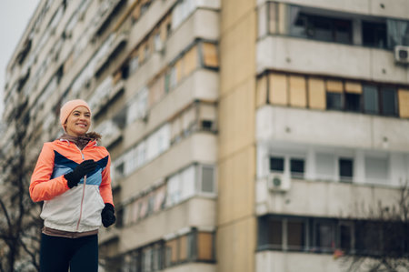 Attractive and athletic young woman training on a cold winter day. Fit sportswoman running in the city on snow at winter.の写真素材