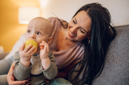 Adorable small baby boy and his mother enjoying moments of love and affection and learning to eat...