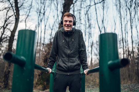 Redhead athlete training in a forest while wearing warm jacket sportswear and using headphones....
