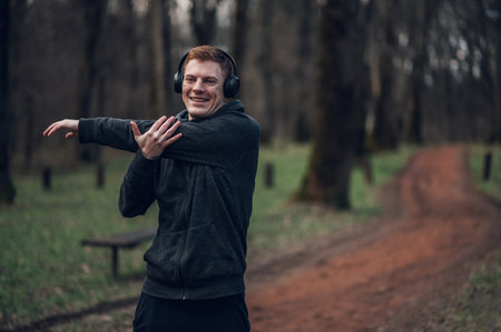 Young redhead man working out in the nature while doing fitness exercises in a forest environment....