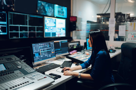 Middle aged woman TV editor working with vision mixer in a television broadcast room. TV engineer at...