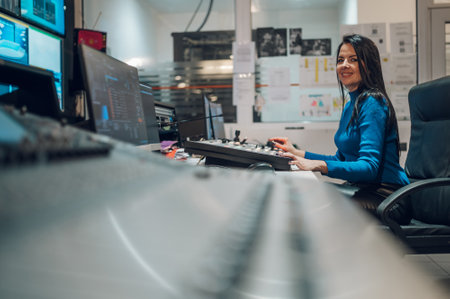 Middle aged woman TV editor working with vision mixer in a television broadcast room. TV engineer at editor in studio. Vision mixing panel in a television studio.の写真素材