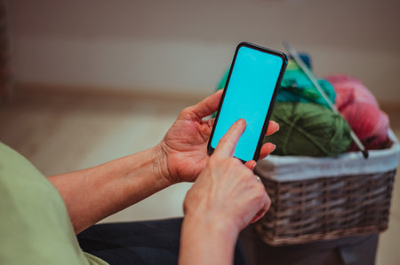 Close up of a wrinkled hands of a senior woman holding a smartphone screen. Mockup concept. Space...