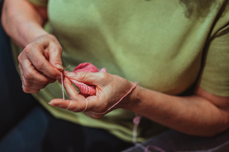 Hands of senior woman knitting a vintage wool quilt and enjoying her free time. Focus on the senior woman hands. Hobby free time activity concept.の写真素材