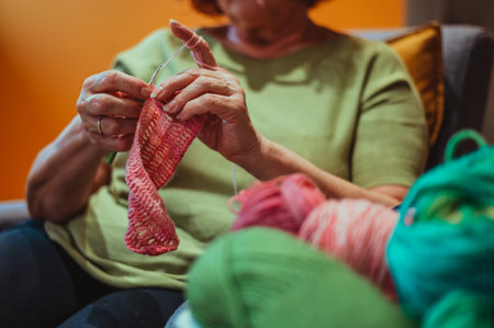 Hands of senior woman knitting a vintage wool quilt and enjoying her free time. Focus on the senior woman hands. Hobby free time activity concept.の写真素材