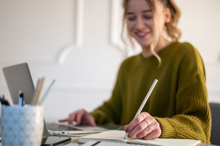 Beautiful young woman using a laptop while working from home in a home office. Cozy office...
