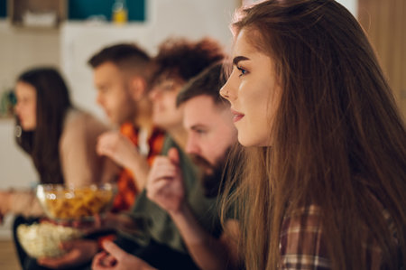 Friends relaxing together at home and watching television and eating snacks. Watching interesting...