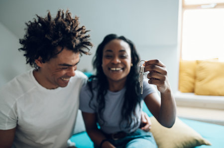 Happy african american couple holding and showing keys of their new apartment house. Buying...