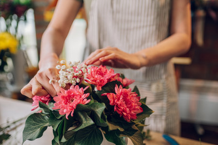 Beautiful young woman florist making a fashionable flower box bouquet for a client special occasion. Beautiful bouquet of mixed flowers. Floral shop concept.の写真素材