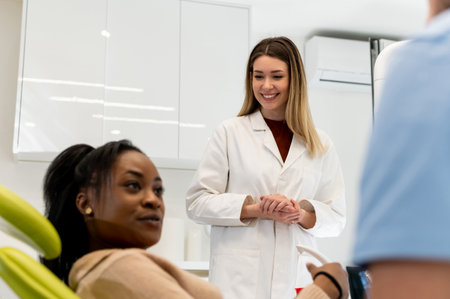 Male dentist in dental office talking with female patient and preparing her for treatment. Explaining the procedure of new dental implants. Focus on a maleの写真素材