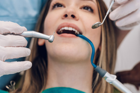 Young professional man doctor dentist working with a woman patient in dental clinic. Competent stomatologist using sterile equipment while fixing patient teeth. Close shot of a patient.の写真素材