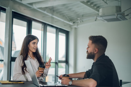 Smart focused young businesswoman discussing online project on a laptop with motivated male colleague while in the office. Discussing new project or task. Sharing information.の写真素材
