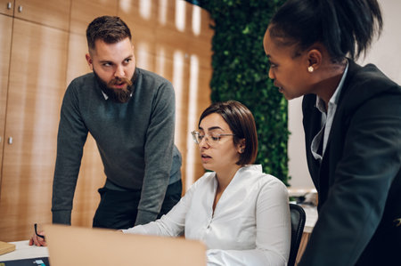 Focused multiracial businesspeople gather at desk brainstorming and discussing company financial paperwork at meeting together. Having a briefing in boardroom.の写真素材