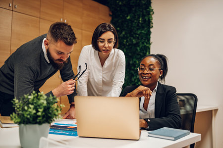 Cheerful multiracial coworkers smiling and working with documents while having a meeting in the...