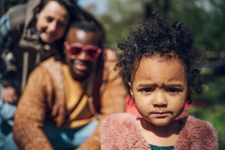 Multiracial family concept. Black father and white mother playing with their daughter in the park and spending the day together. Focus on a baby girl.の写真素材