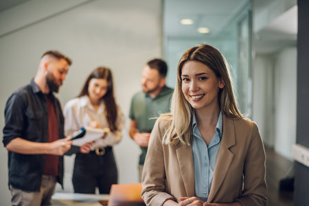 Portrait of beautiful caucasian business woman standing in front of business team at modern agency. Happy smiling ceo manager in the modern office. Leader, boss, CEO, financial corporate advisor.の写真素材