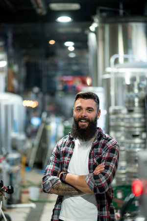 Portrait of male brewer standing at brewery factory. Factory worker with industrial equipment at the...
