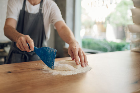 Male worker in a pizza place preparing dough for pizza on counter top. Man hands working with dough and flour. Pizzeria.の写真素材
