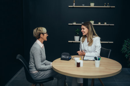 Smiling female doctor in consultation with a senior woman patient in a modern officeの写真素材