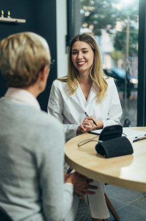 Smiling female doctor in consultation with a senior woman patient in a modern officeの写真素材