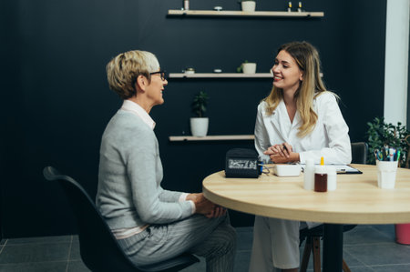 Smiling female doctor in consultation with a senior woman patient in a modern officeの写真素材