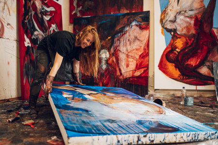 Portrait of a gorgeous redhead female artist working on several art projects on her bright studio....