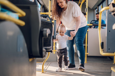 Plus size mother and a son walking in a bus in the city during a day. Happy family using a public transport. Travel, tourism, family and people concept. Mom holding her baby boy while walking.の写真素材
