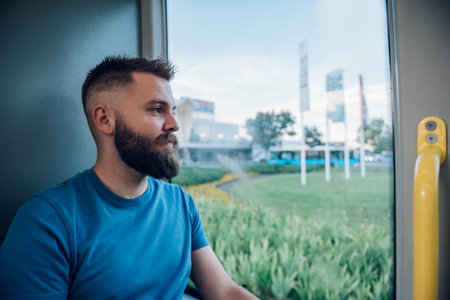 Portrait of a mansitting in a bus next to the window. Everyday life and commuting to work by public transportation. Riding a bus in the city.の写真素材