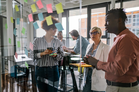 Positive multiracial group of business people working together on a new project and writing main...