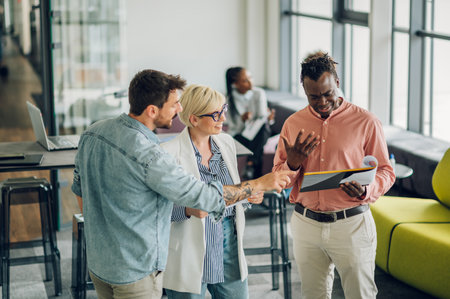 Three multiracial business people are discussing about business graph in the office during a meeting. Business discussing and planning strategy concept. Corporate team brainstorming with chart.の写真素材