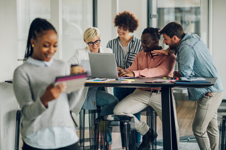 Portrait of confident young business woman standing in office and using a tablet. Focus on a multiracial colleagues discussing work in the background. Meeting in the office.の写真素材
